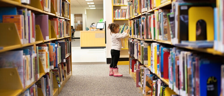 A young child browsing library bookshelves