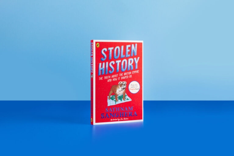 A photograph of the new book Stolen History by Sathnam Sanghera. The book cover is bright red with an illustration of an English bulldog standing on top of a map of the world. The book is in front of a light blue background and atop a darker blue surface.