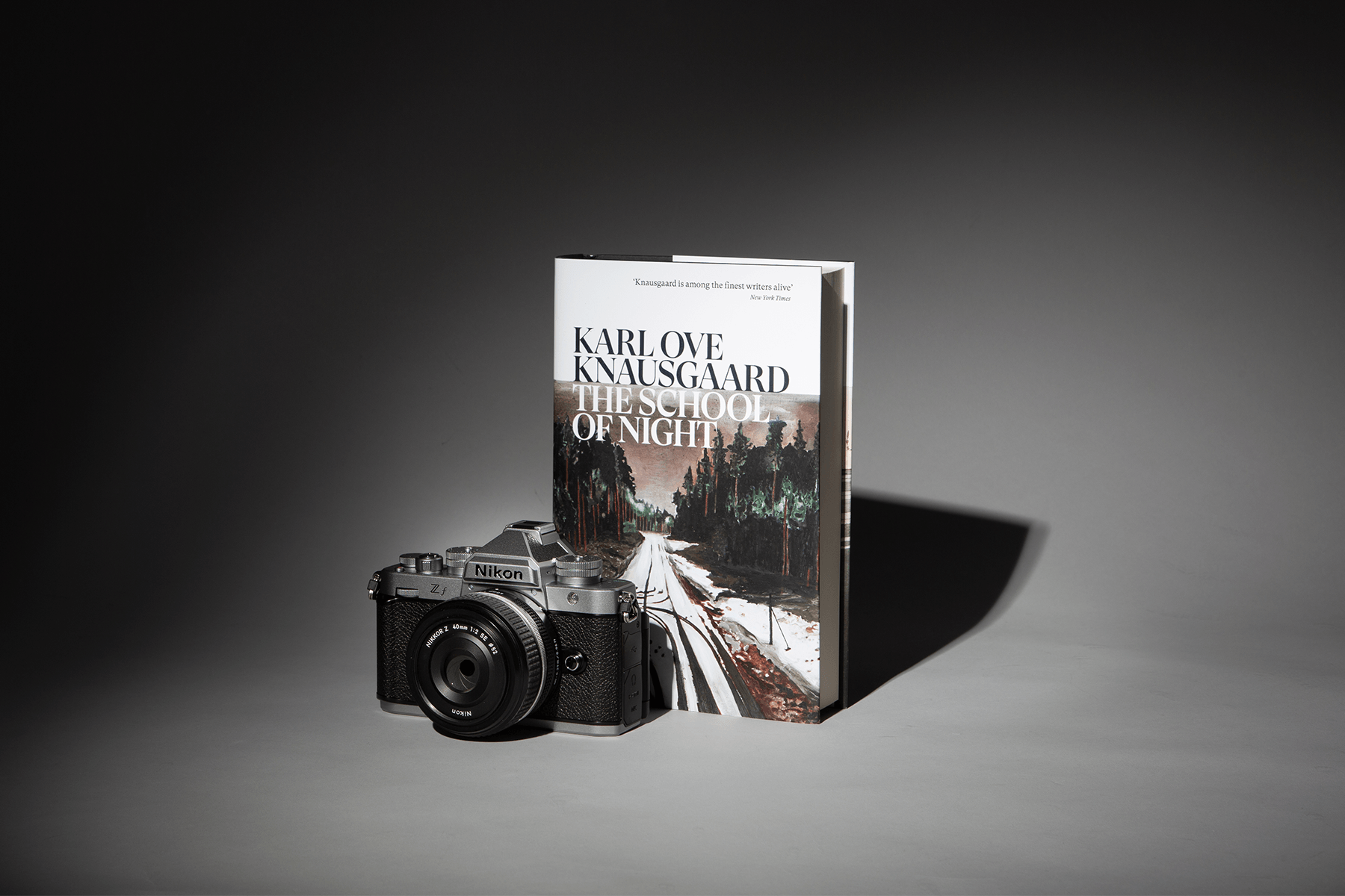 The Nikon Z f camera and a hardback of The School of Night spotlit against a grey background